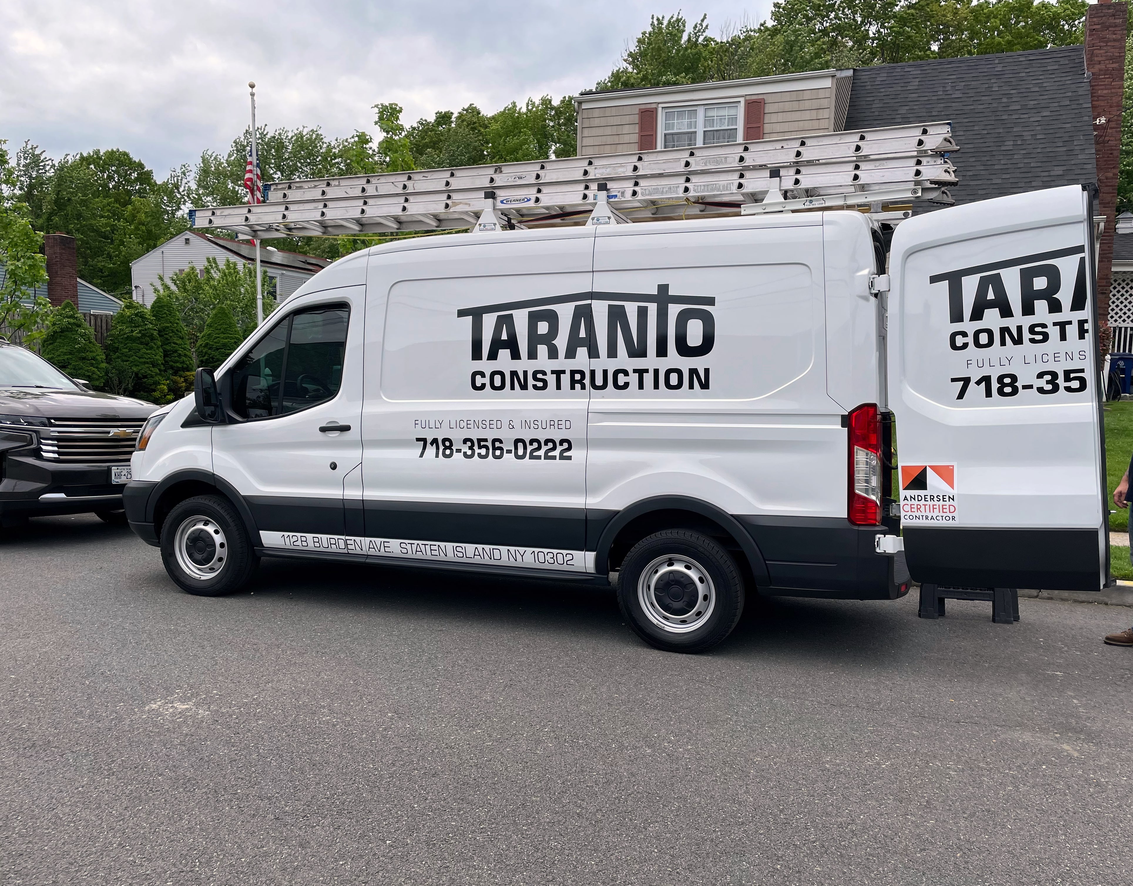 White Taranto Construction van with ladder rack parked on a residential street